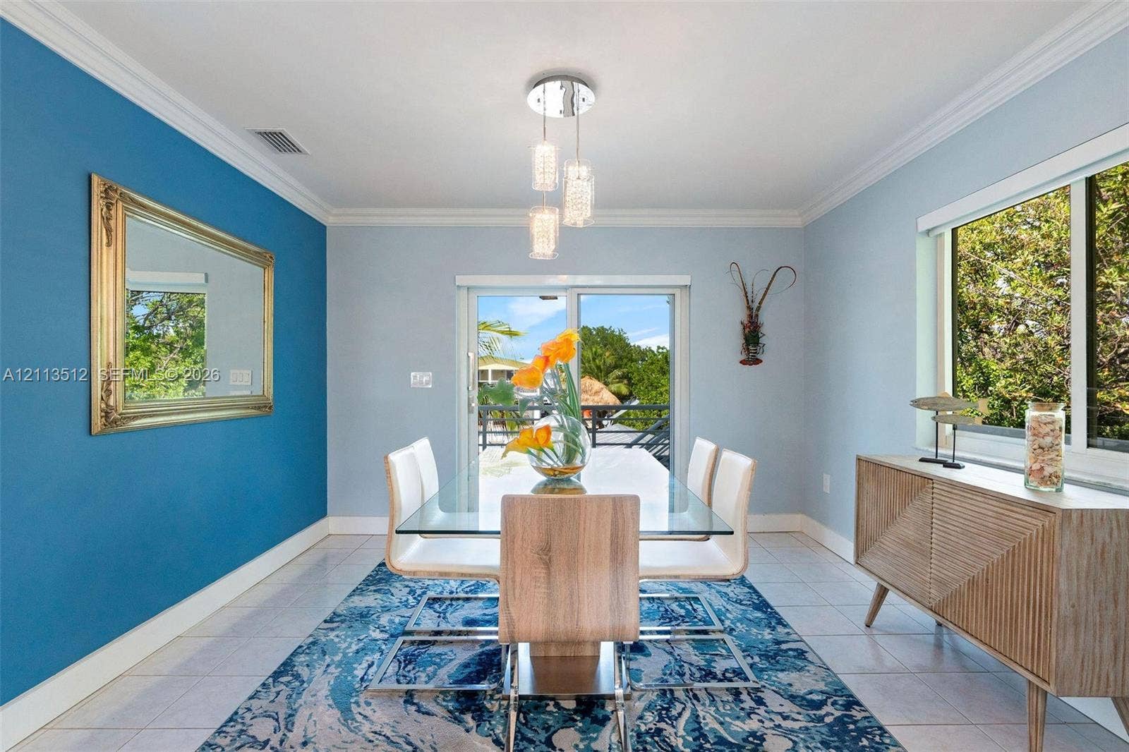 Key Largo, FL 33037 Dining area featuring crown molding, a modern three-light glass pendant fixture, sliding glass doors, and light-toned tile flooring