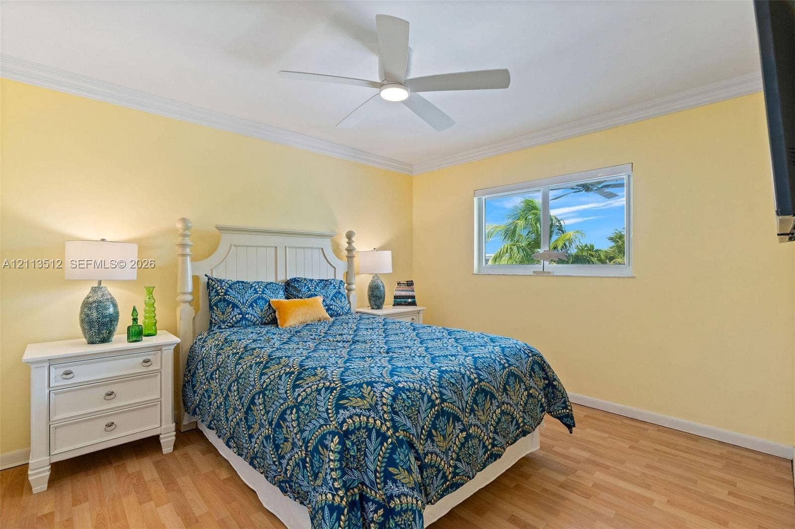 Key Largo, FL 33037 Room featuring wood-finish flooring, crown molding, a central ceiling fan with integrated lighting, and a window with exterior greenery