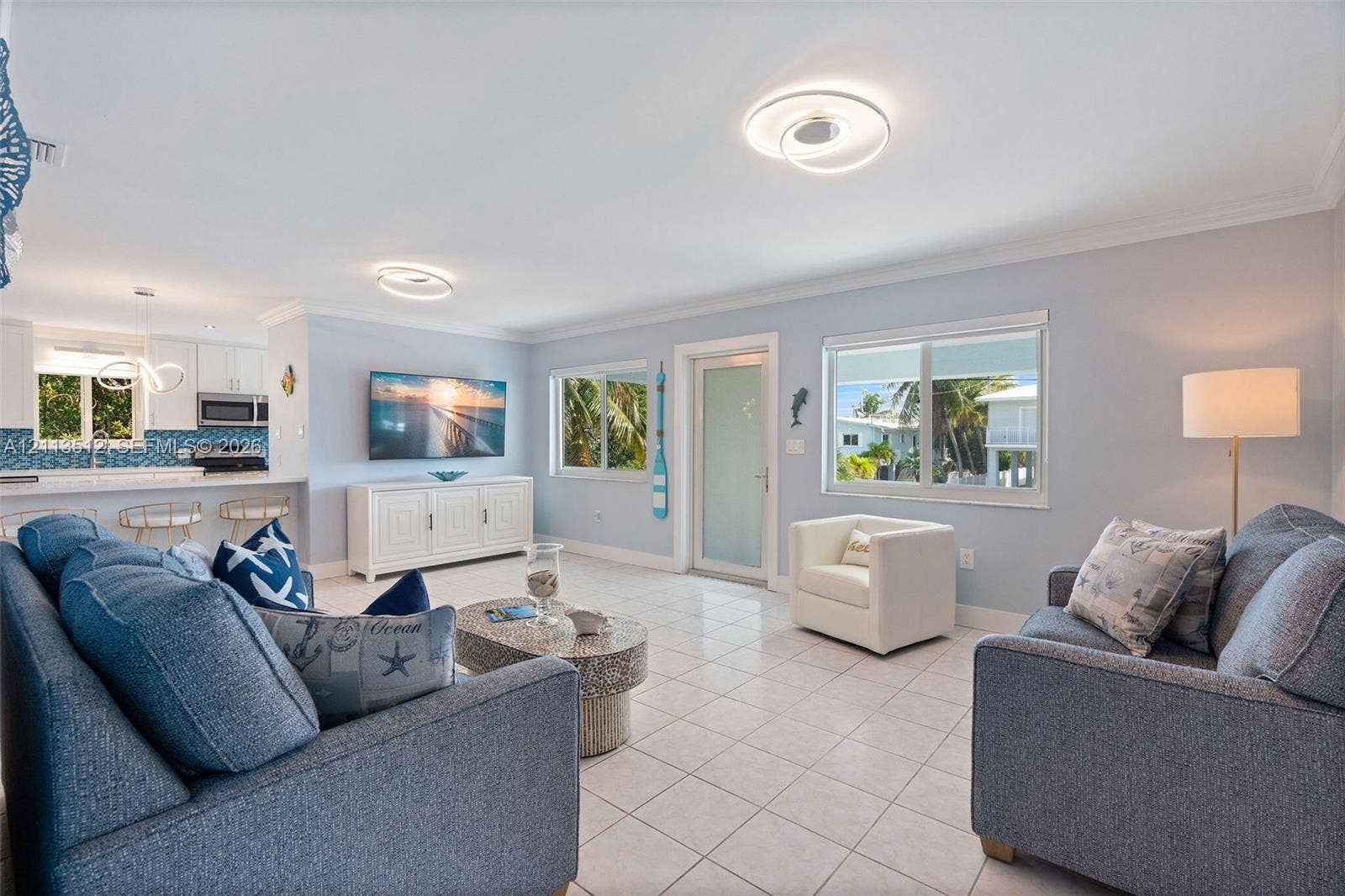 Key Largo, FL 33037 Open-concept interior featuring light-colored tile flooring, contemporary circular LED flush-mount lighting, and large windows with horizontal panes