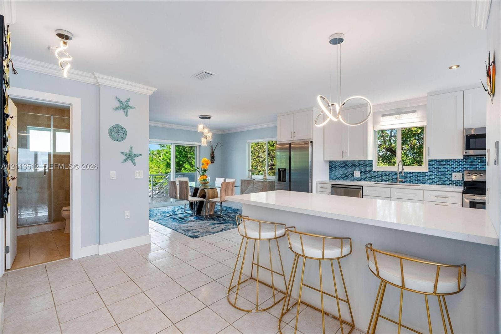 Key Largo, FL 33037 Kitchen featuring a white quartz countertop island, white cabinetry, blue geometric tile backsplash, and stainless steel appliances