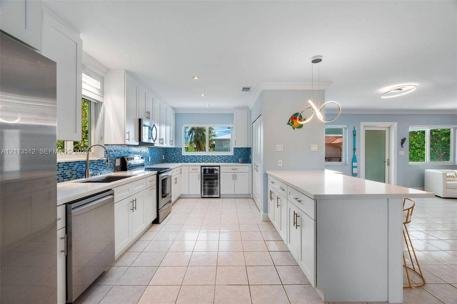 Key Largo, FL 33037 Kitchen featuring white shaker-style cabinetry, quartz countertops, a blue glass tile backsplash, stainless steel appliances, and a built-in beverage refrigerator
