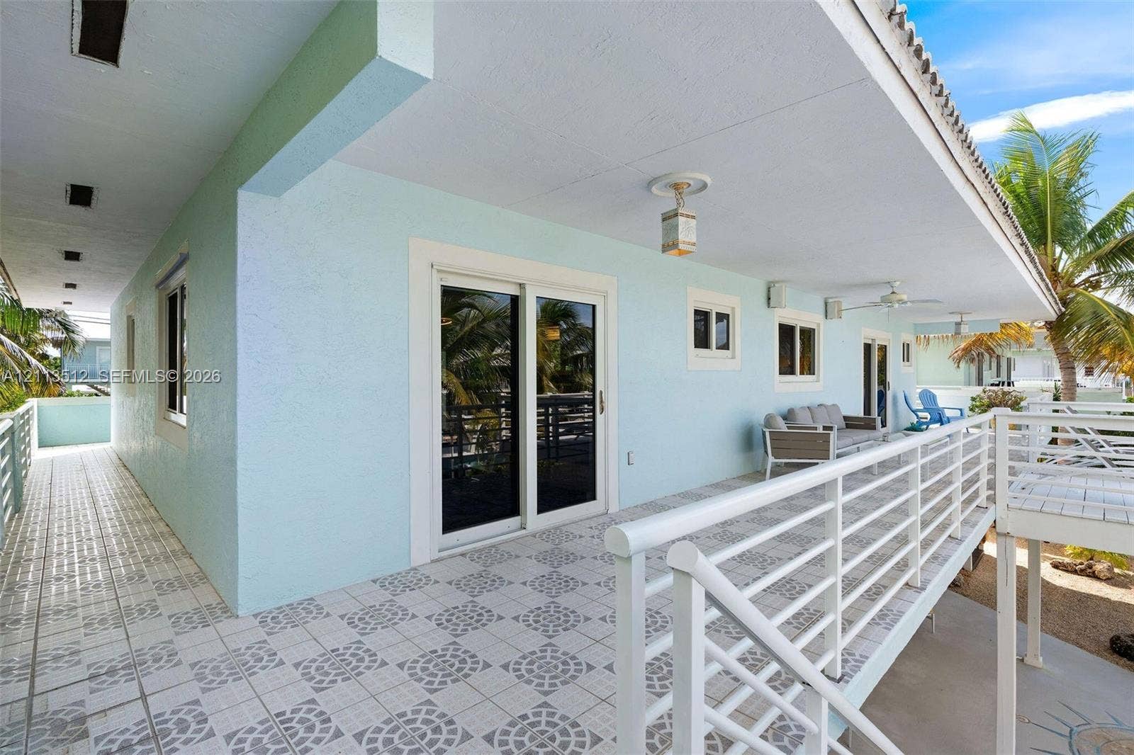 Key Largo, FL 33037 Covered exterior balcony featuring patterned tile flooring, a white metal railing, recessed ceiling lighting, and glass sliding door access