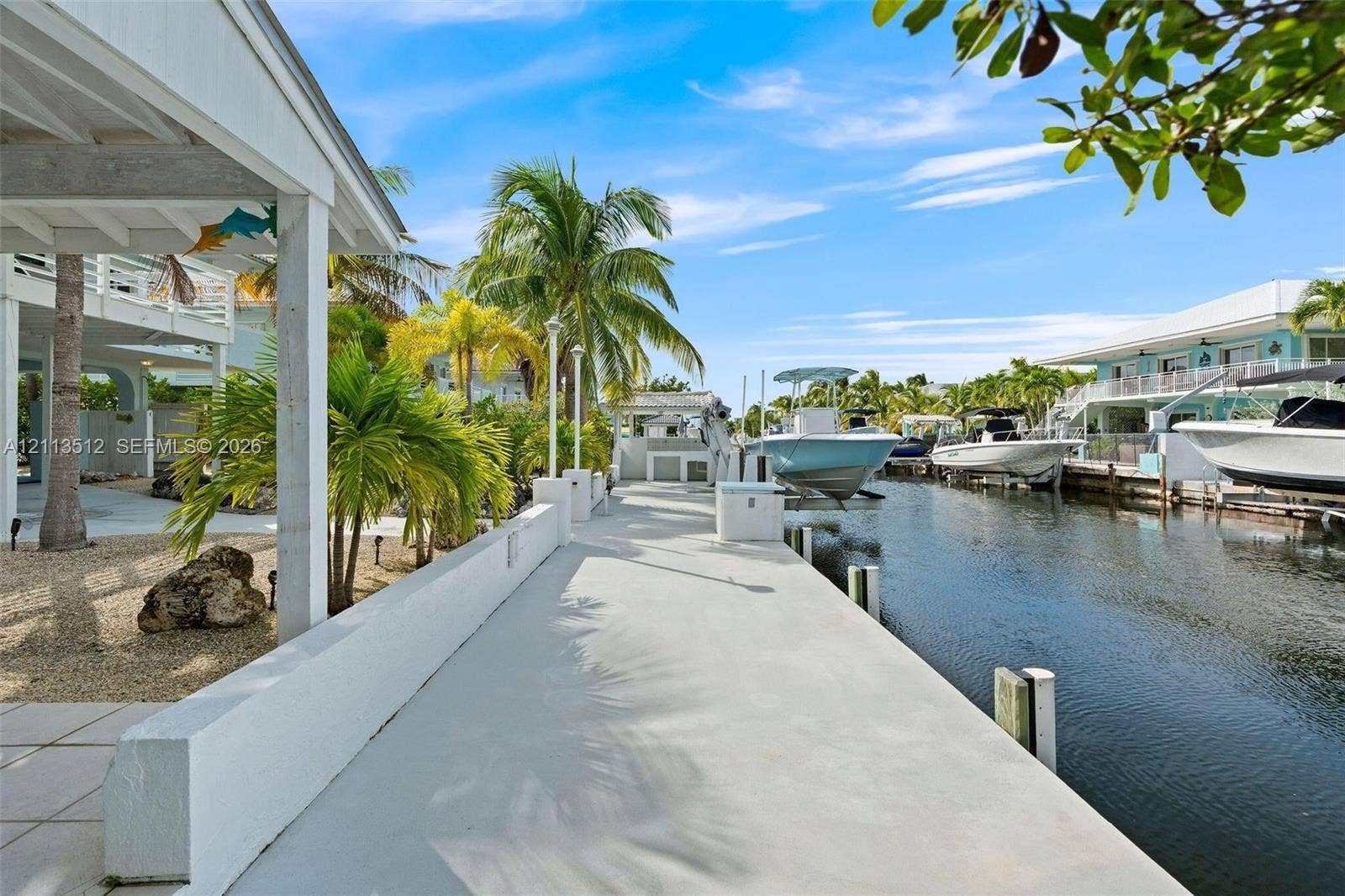 Key Largo, FL 33037 Concrete waterfront bulkhead featuring a paved walking path, integrated light fixtures, and a direct-access boat lift