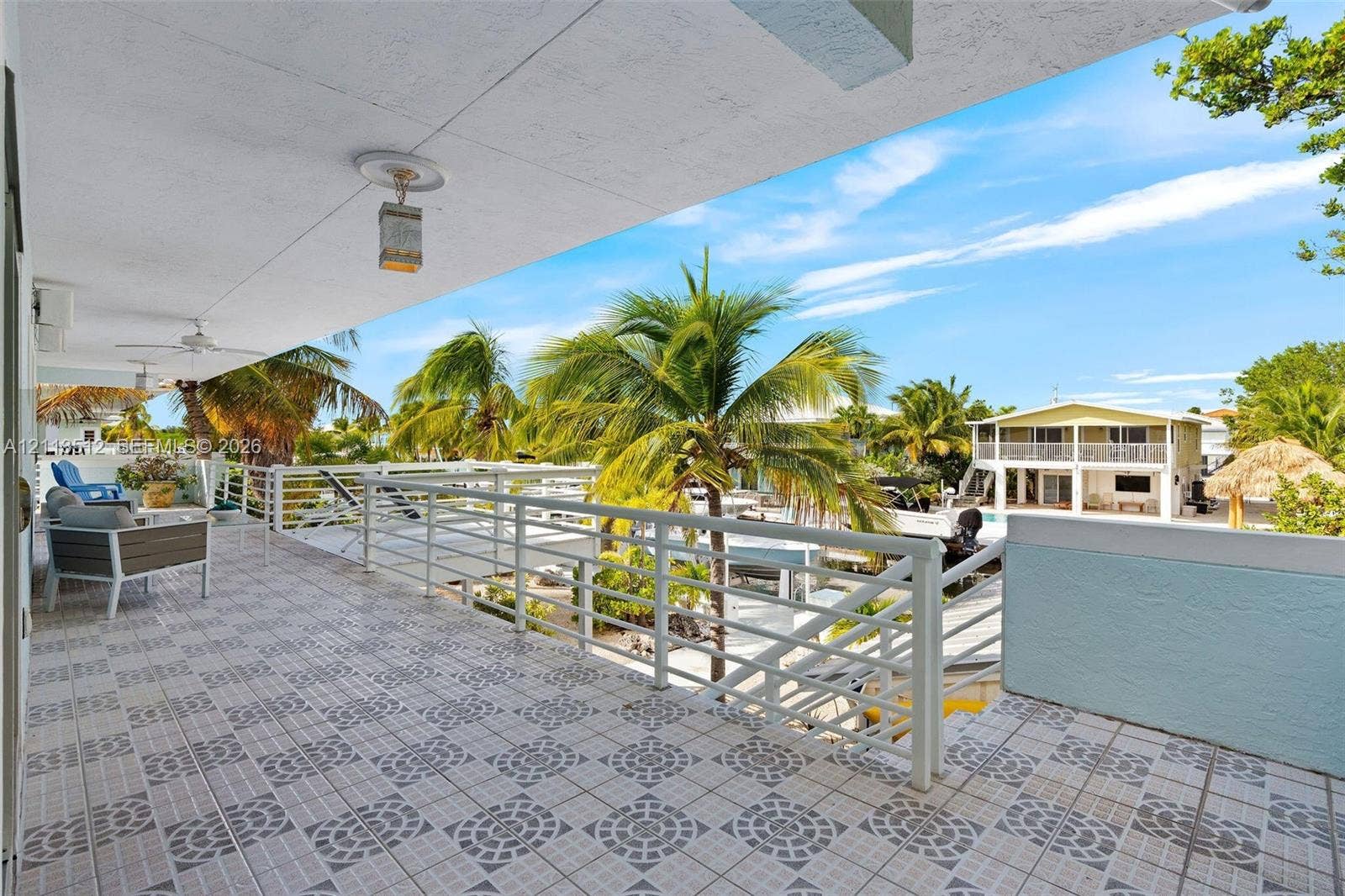 Key Largo, FL 33037 Covered balcony featuring patterned ceramic tile flooring, horizontal metal railings, and dual ceiling-mounted light fixtures