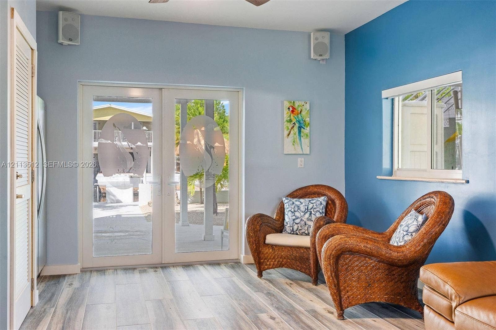Key Largo, FL 33037 Double French doors featuring frosted glass panels with etched tropical motifs, wood-finish flooring, two wall-mounted speakers, and a louvered closet door