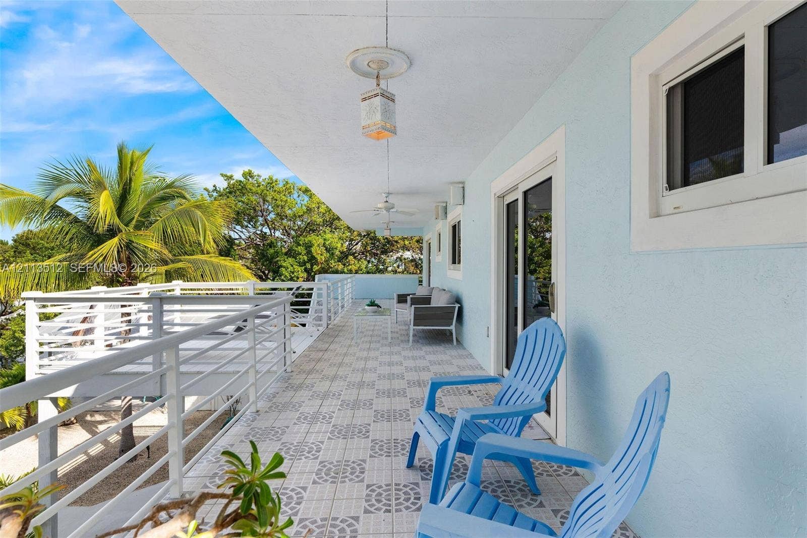 Key Largo, FL 33037 Covered exterior balcony featuring patterned tile flooring, white horizontal-rail fencing, and mounted light fixtures