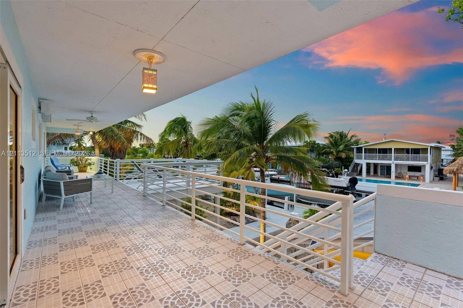 Key Largo, FL 33037 Covered exterior balcony featuring patterned tile flooring, white metal railing, and ceiling-mounted lighting