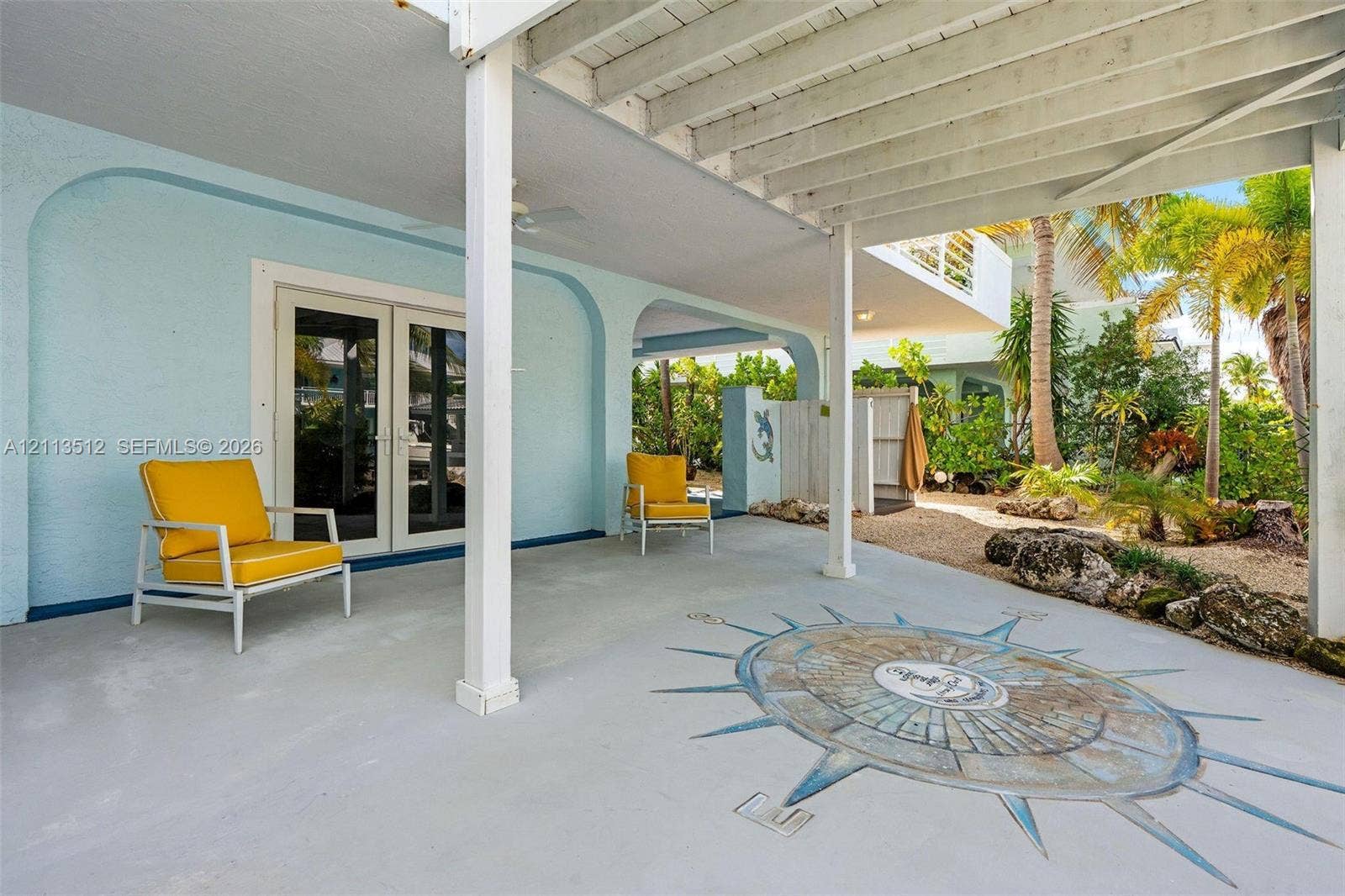Key Largo, FL 33037 Covered patio featuring a concrete floor with a decorative compass inlay, arched structural supports, French doors, and an outdoor shower area