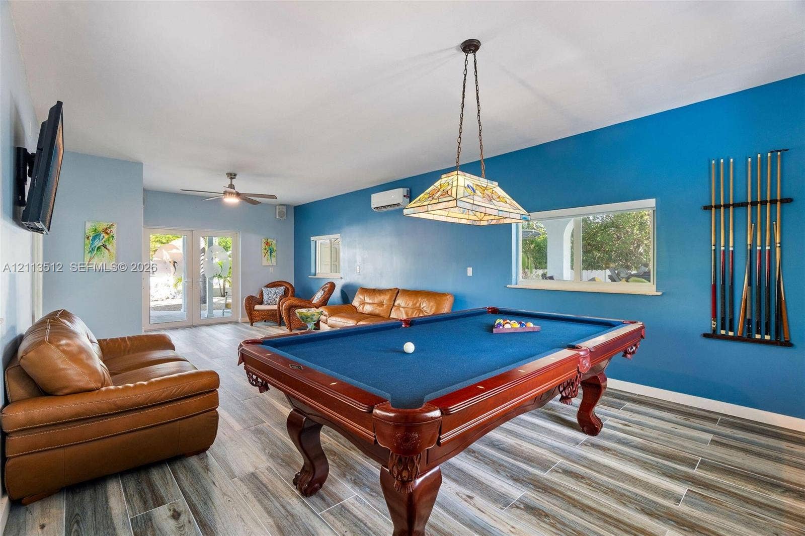 Key Largo, FL 33037 Wood-finish flooring, stained-glass pendant lighting, wall-mounted ductless air conditioning unit, and glass-paneled exterior door