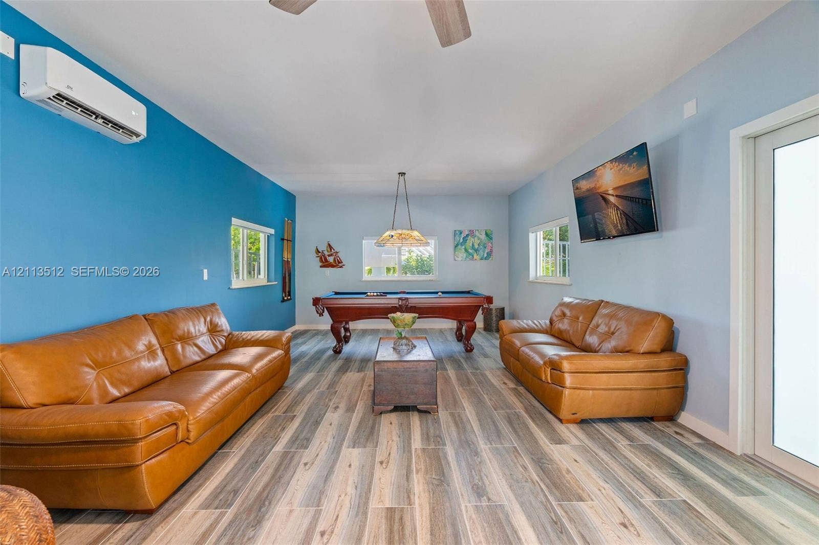 Key Largo, FL 33037 Wood-finish flooring, wall-mounted ductless air conditioning unit, ceiling-mounted light fixture, and multiple windows
