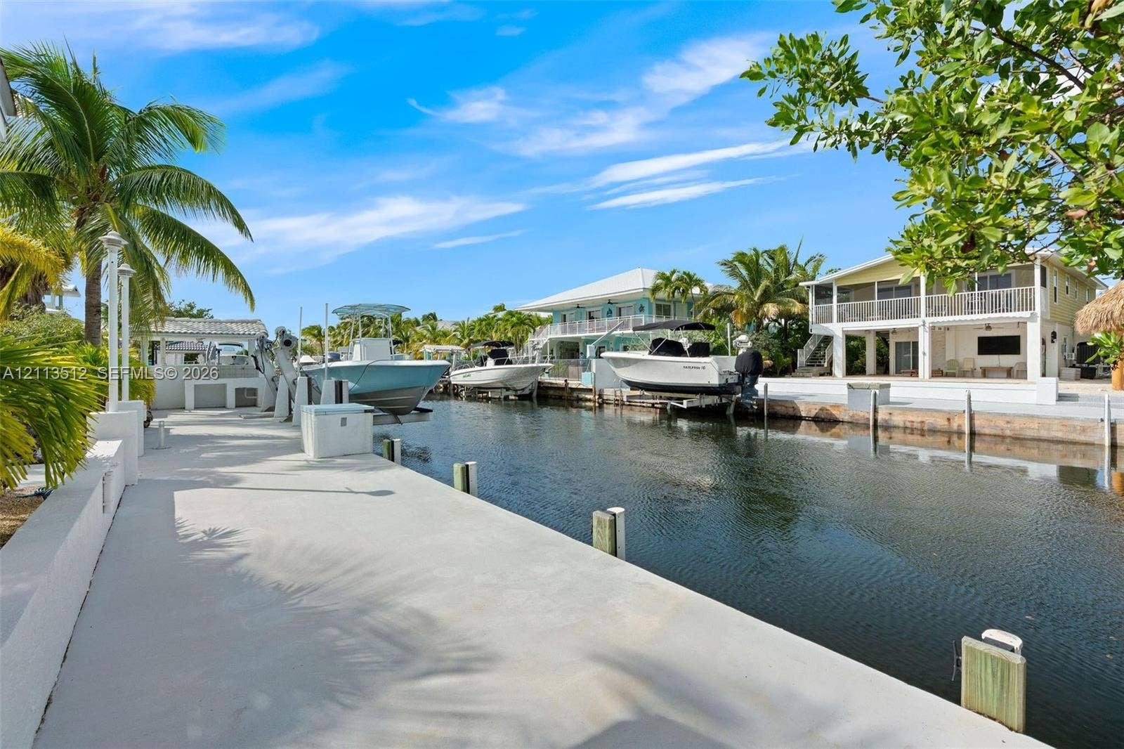 Key Largo, FL 33037 Concrete waterfront dock featuring boat lifts, utility pedestals, and access to a canal