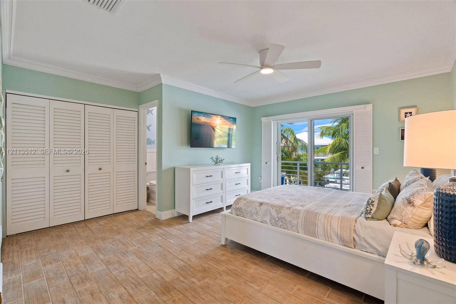 Key Largo, FL 33037 Wood-finish tile flooring, white louvered-door closets, crown molding, ceiling fan, and sliding glass doors with balcony access