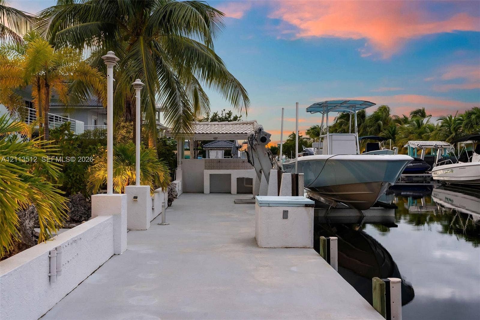 Key Largo, FL 33037 Concrete dock featuring a boat lift, built-in storage unit, and pedestal lighting