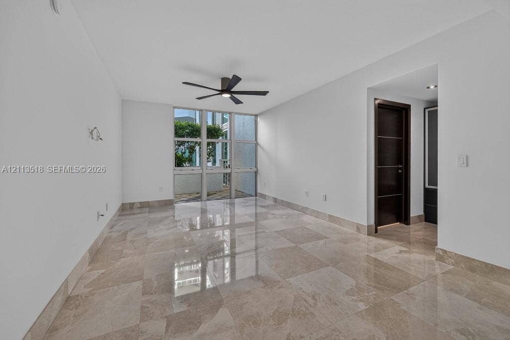 3131 NE 188th Street, #1-303, Aventura, FL 33180 Interior space featuring large-format stone tile flooring, floor-to-ceiling windows, and a matte black ceiling fan