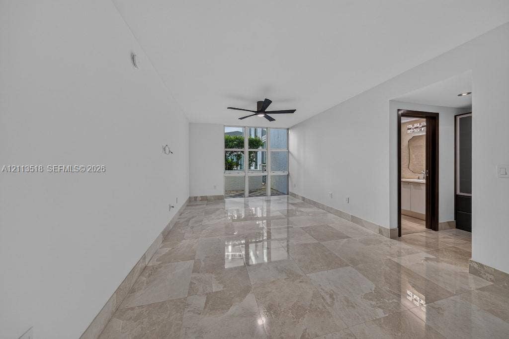 3131 NE 188th Street, #1-303, Aventura, FL 33180 Interior space featuring polished natural stone flooring, floor-to-ceiling windows, and a matte black ceiling fan