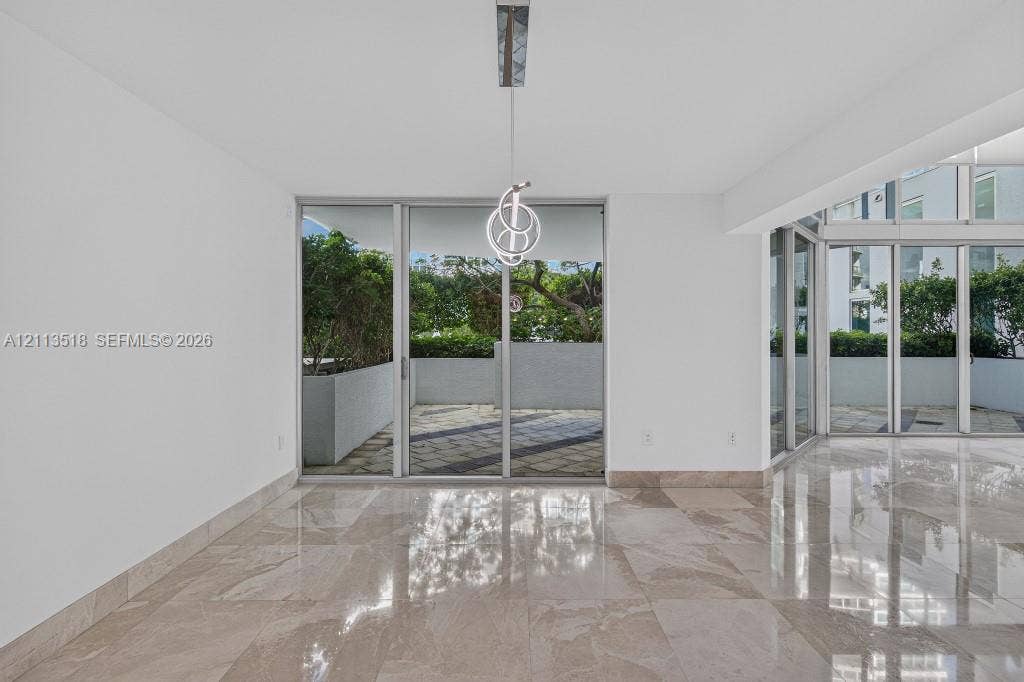 3131 NE 188th Street, #1-303, Aventura, FL 33180 Polished stone flooring, floor-to-ceiling glass sliding doors, built-in contemporary pendant lighting, and an expansive exterior terrace with masonry planters