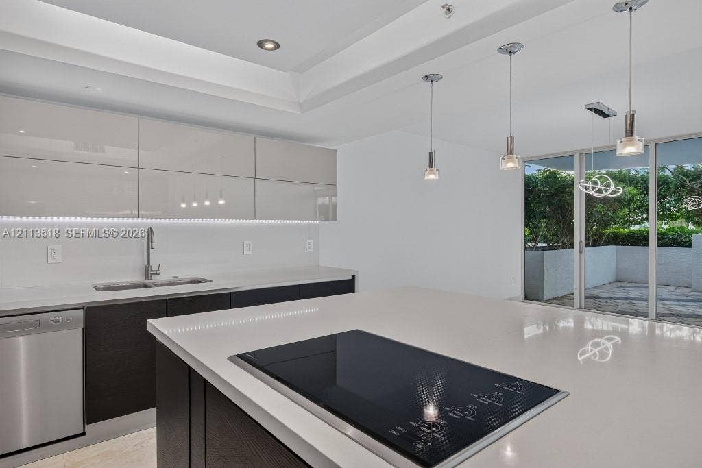 3131 NE 188th Street, #1-303, Aventura, FL 33180 Kitchen featuring high-gloss cabinetry, stone countertops, a stainless steel dishwasher, a built-in cooktop, and recessed tray ceiling lighting