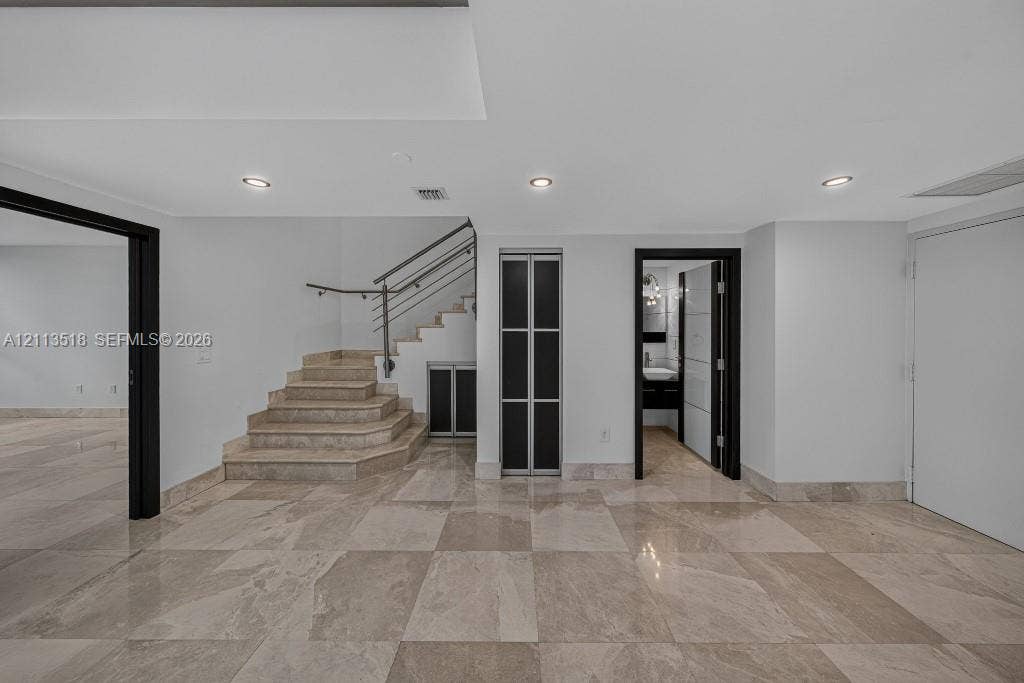 3131 NE 188th Street, #1-303, Aventura, FL 33180 Polished stone flooring, recessed lighting, staircase with metal railings, and contrasting dark-framed doorways