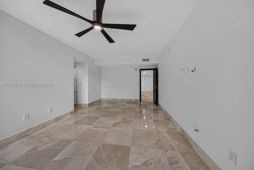 3131 NE 188th Street, #1-303, Aventura, FL 33180 Large-format stone tile flooring with matching stone wall trim, featuring a modern matte black five-blade ceiling fan with integrated lighting