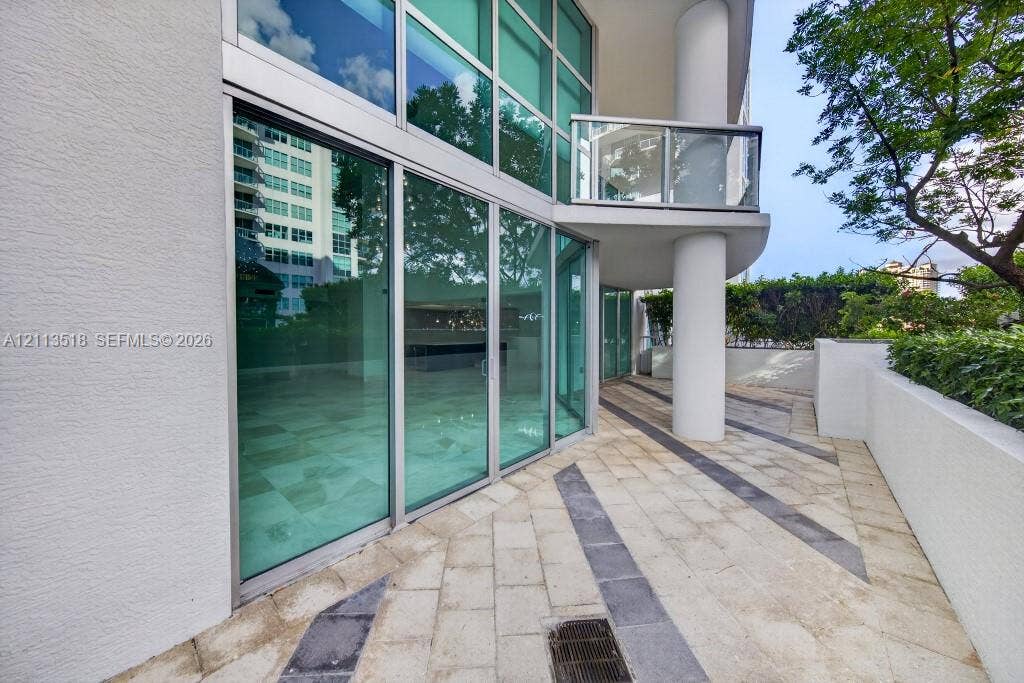 3131 NE 188th Street, #1-303, Aventura, FL 33180 Outdoor terrace featuring floor-to-ceiling glass paneling, geometric stone paver inlay, concrete structural column, and glass-railing balcony