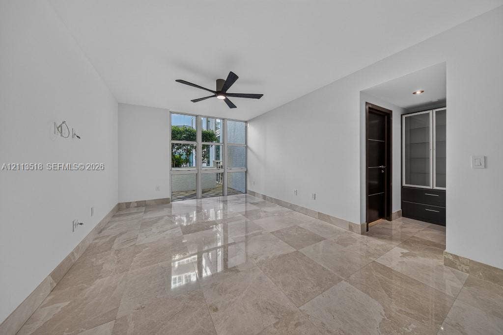 3131 NE 188th Street, #1-303, Aventura, FL 33180 Polished stone flooring, floor-to-ceiling windows, dark wood-finish interior doors, recessed ceiling lighting, and built-in cabinetry with glass-front shelving