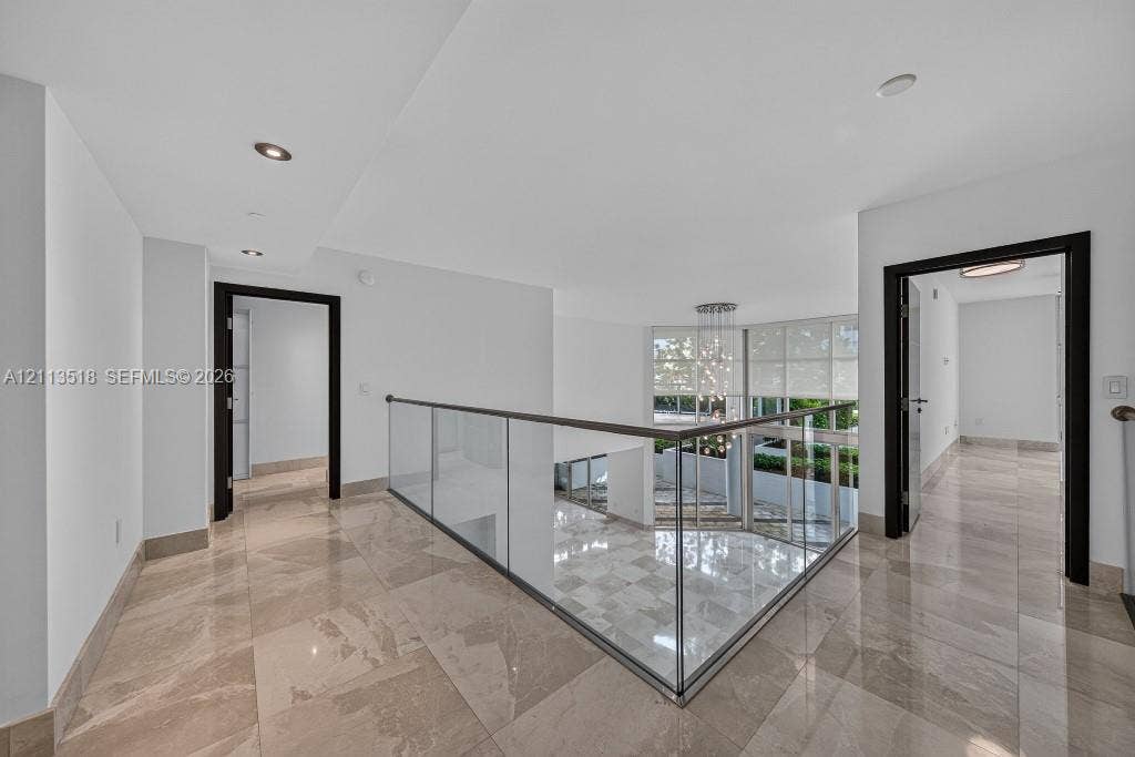 3131 NE 188th Street, #1-303, Aventura, FL 33180 Polished tile flooring, glass panel railing with a metal handrail, recessed lighting, and dark-toned door frames