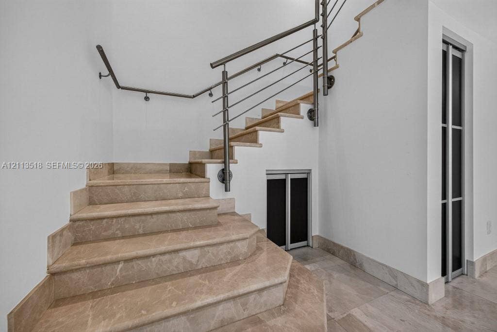 3131 NE 188th Street, #1-303, Aventura, FL 33180 Staircase featuring stone treads, metal industrial-style railing, and built-in storage access