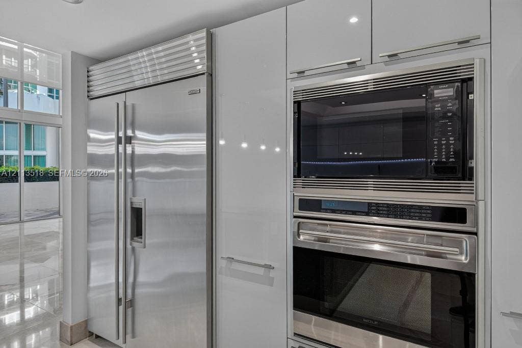 3131 NE 188th Street, #1-303, Aventura, FL 33180 Gloss-finish cabinetry with stainless steel hardware, integrated side-by-side refrigerator, built-in microwave, and wall oven