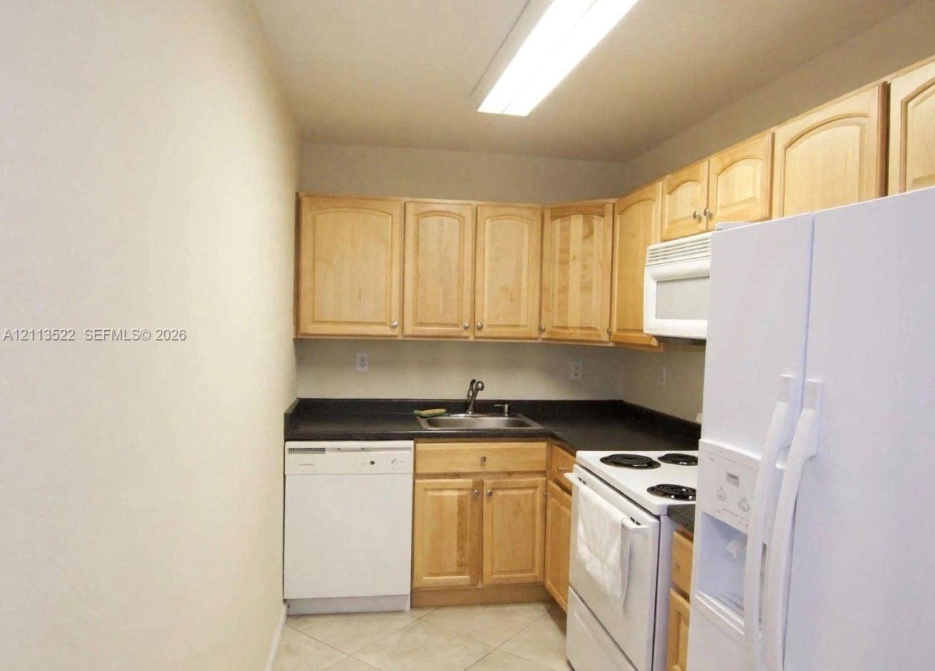405 S Pine Island Road, #105D, Plantation, Plantation, FL 33324 Kitchen featuring light-finish cabinetry, solid surface countertops, a stainless steel sink with a high-arch faucet, and white appliances
