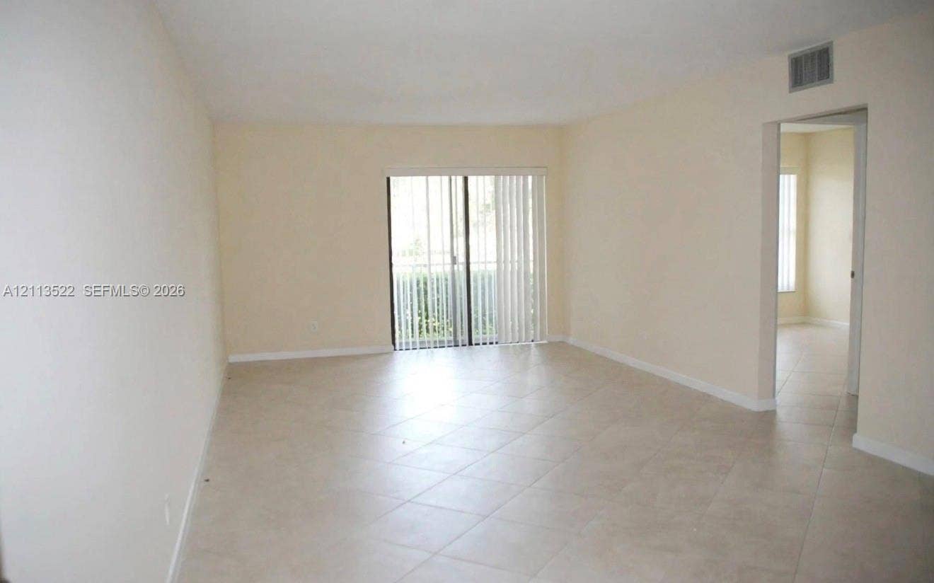 405 S Pine Island Road, #105D, Plantation, Plantation, FL 33324 Neutral-toned interior space featuring diagonal tile flooring and sliding glass doors with vertical blinds