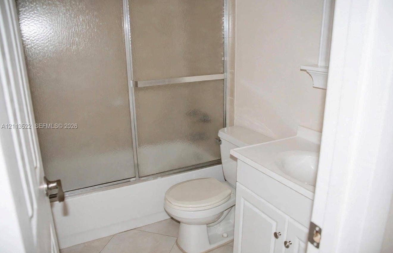 405 S Pine Island Road, #105D, Plantation, Plantation, FL 33324 Bathroom featuring white cabinetry, integrated sink, tub-shower combination with sliding glass doors, and light-toned tile flooring