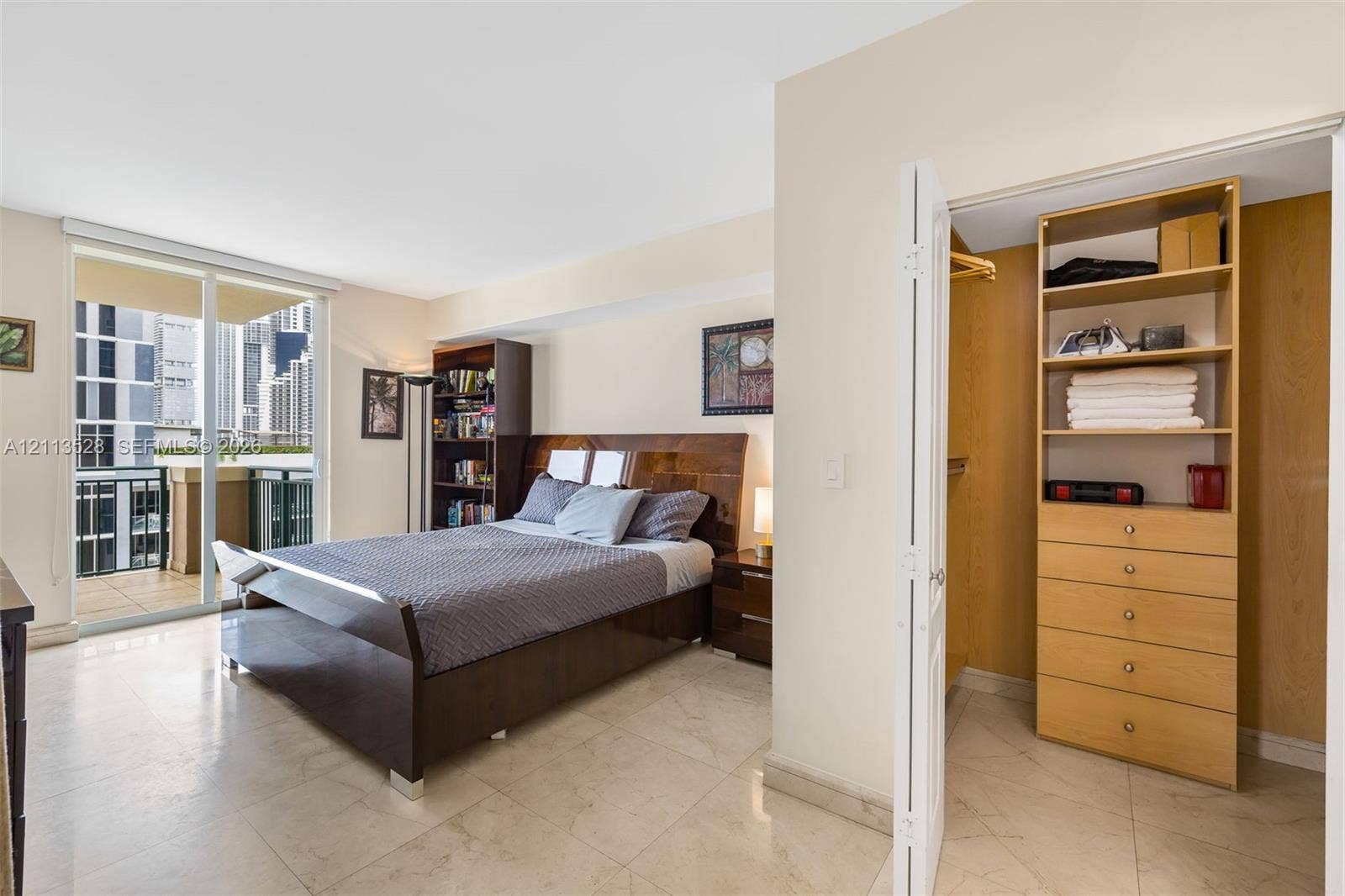 17555 Atlantic Boulevard, #1108, Sunny Isles Beach, Sunny Isles Beach, FL 33160 Sliding glass doors leading to a private balcony, large-format tile flooring, and a walk-in closet featuring built-in wood-finish shelving and drawer storage