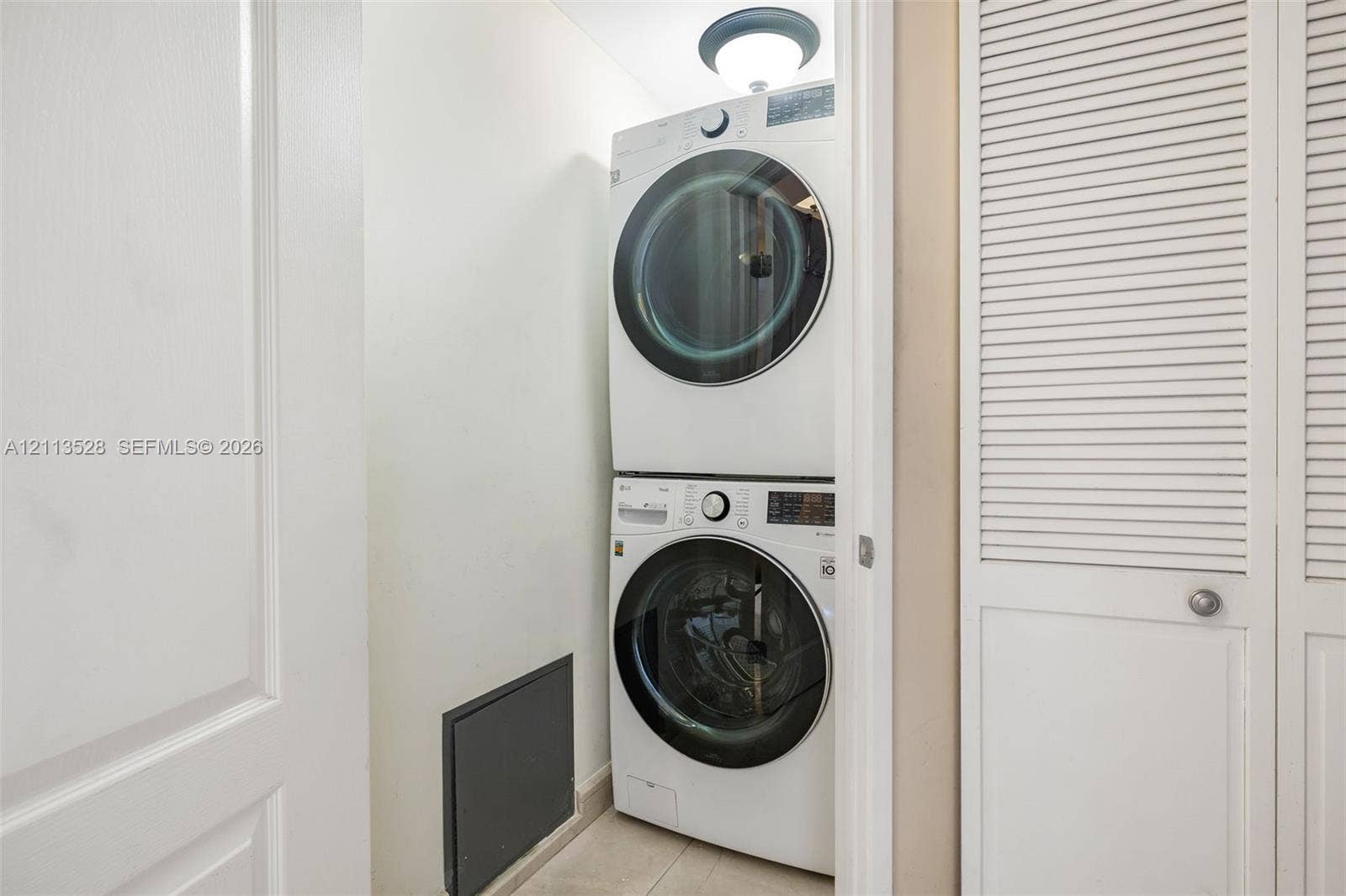 17555 Atlantic Boulevard, #1108, Sunny Isles Beach, Sunny Isles Beach, FL 33160 Stacked front-load laundry unit featuring a circular ceiling-mounted light fixture and white louvered closet doors