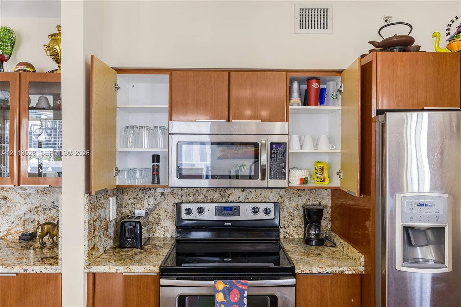 17555 Atlantic Boulevard, #1108, Sunny Isles Beach, Sunny Isles Beach, FL 33160 Kitchen featuring wood-finish cabinetry, natural stone countertops, a stainless steel built-in microwave, a stainless steel range, and a stainless steel refrigerator