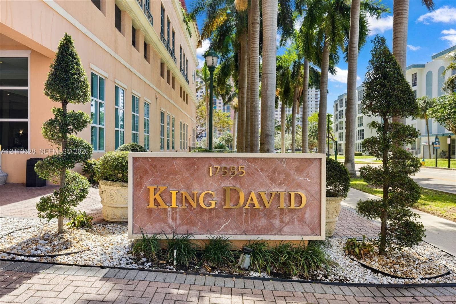 17555 Atlantic Boulevard, #1108, Sunny Isles Beach, Sunny Isles Beach, FL 33160 Custom stone monument sign with raised gold lettering, framed by manicured topiary trees, aggregate rock ground cover, and brick-paver landscaping