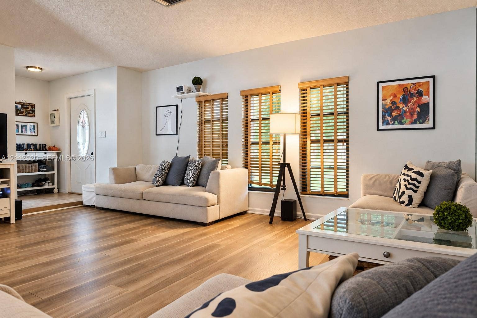 1773 NW 82nd Avenue, Coral Springs, FL 33071 Living area featuring wood-finish flooring, white walls, and triple windows with horizontal blinds
