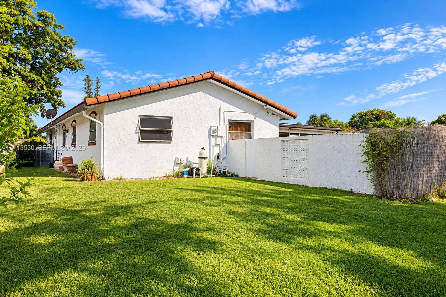 1773 NW 82nd Avenue, Coral Springs, FL 33071 Stucco exterior with a terra cotta tile roof, expansive lawn, and a white privacy wall