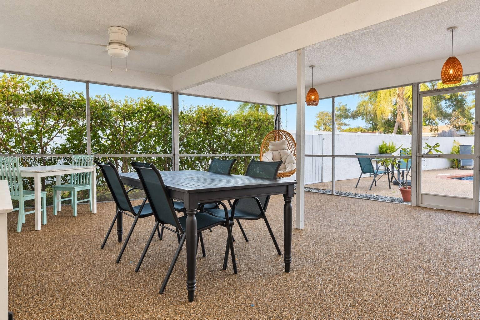 1773 NW 82nd Avenue, Coral Springs, FL 33071 Screened-in patio featuring textured aggregate flooring, dual pendant lighting, a ceiling fan, and a glass-paneled entry door