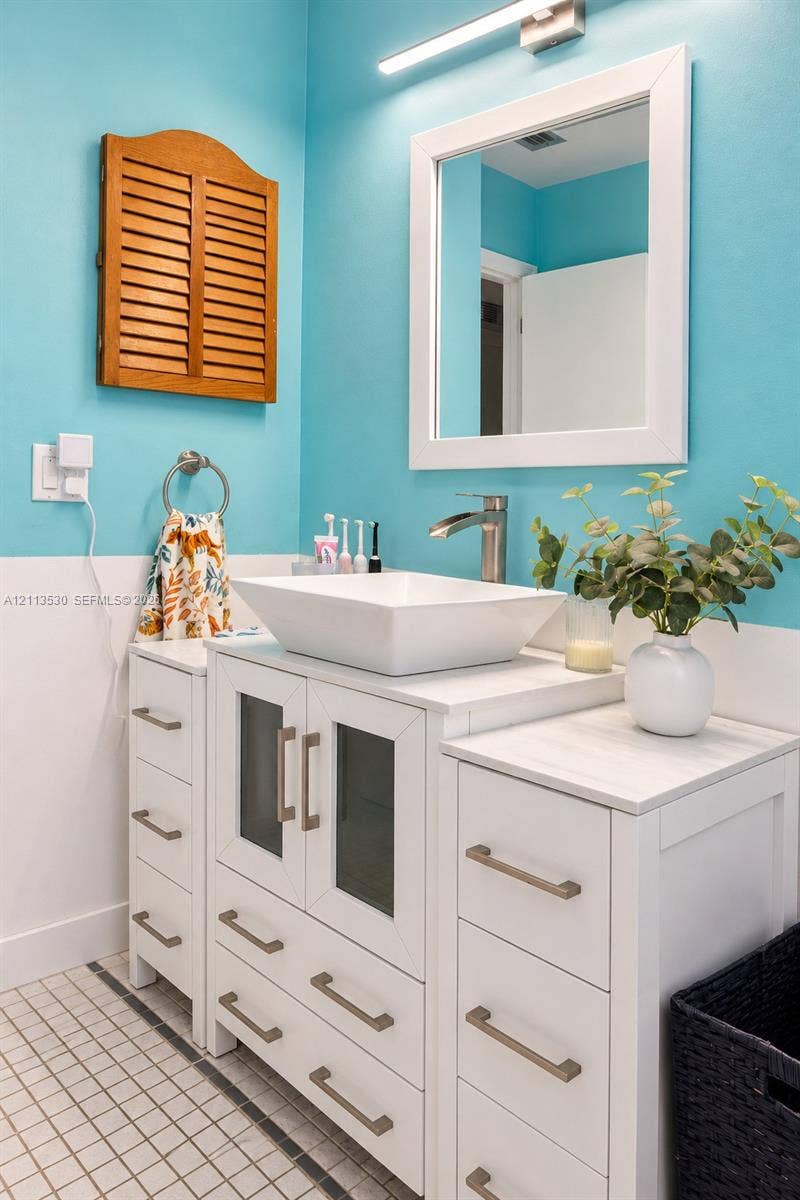 1773 NW 82nd Avenue, Coral Springs, FL 33071 White vanity featuring a rectangular vessel sink, stone-finish countertop, cabinet doors with glass insets, and brushed metal hardware