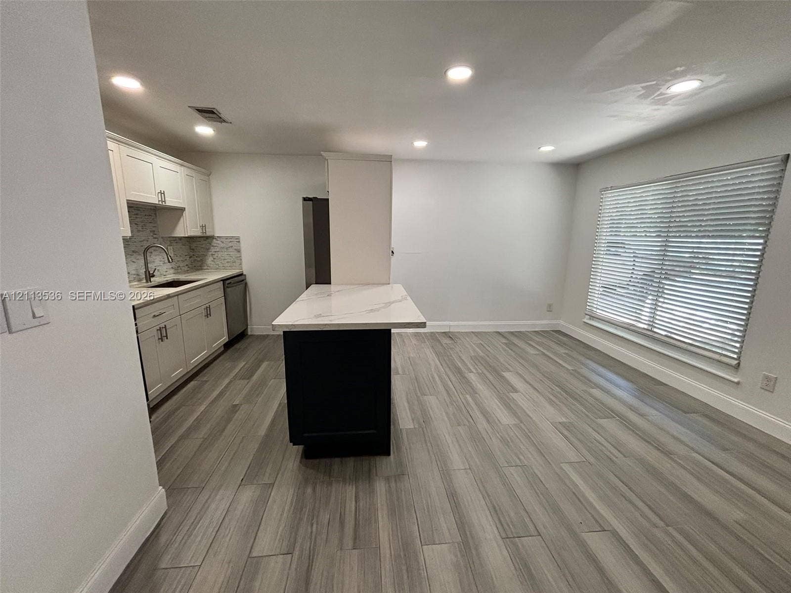 4840 SW 25th Avenue, #4840, Dania, Dania Beach, FL 33312 Kitchen featuring white cabinetry, a contrasting dark central island with a stone-finish countertop, wood-finish flooring, recessed lighting, and a window with blinds