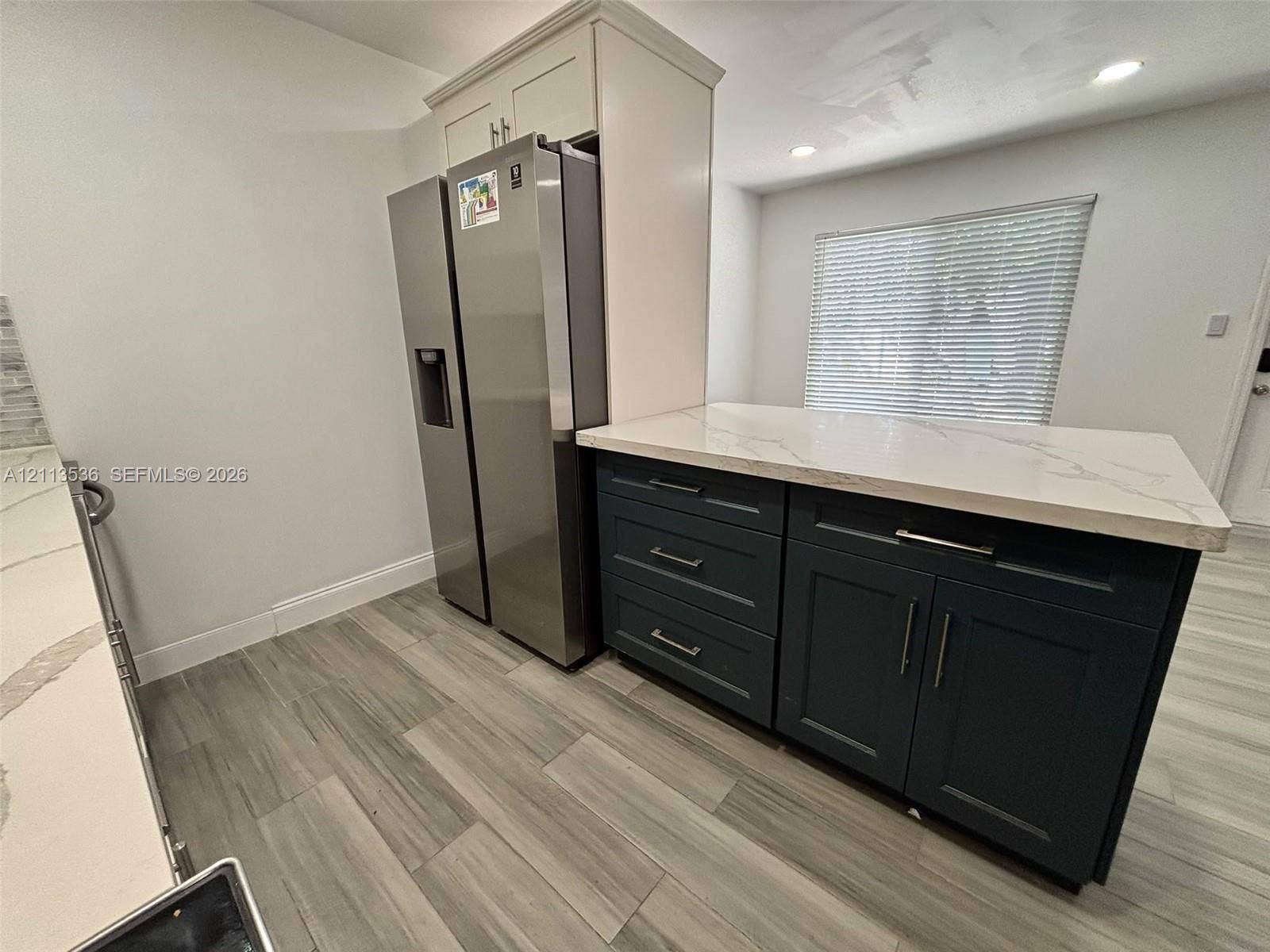 4840 SW 25th Avenue, #4840, Dania, Dania Beach, FL 33312 Kitchen featuring dark-toned cabinetry, light-colored countertops with veining, stainless steel refrigerator, wood-finish flooring, and recessed ceiling lighting