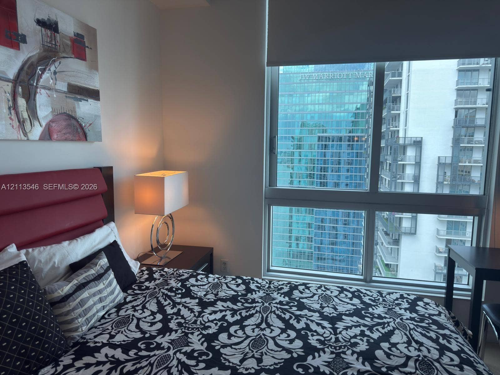 Floor-to-ceiling windows featuring urban scenery and integrated roller shade
