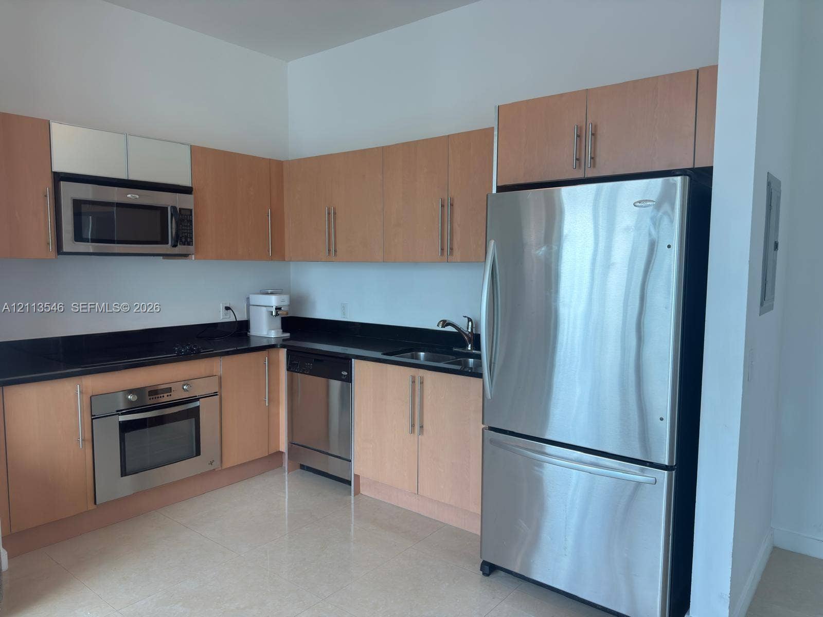 Kitchen featuring flat-panel wood-finish cabinetry, dark solid-surface countertops, stainless steel appliances, and tile flooring