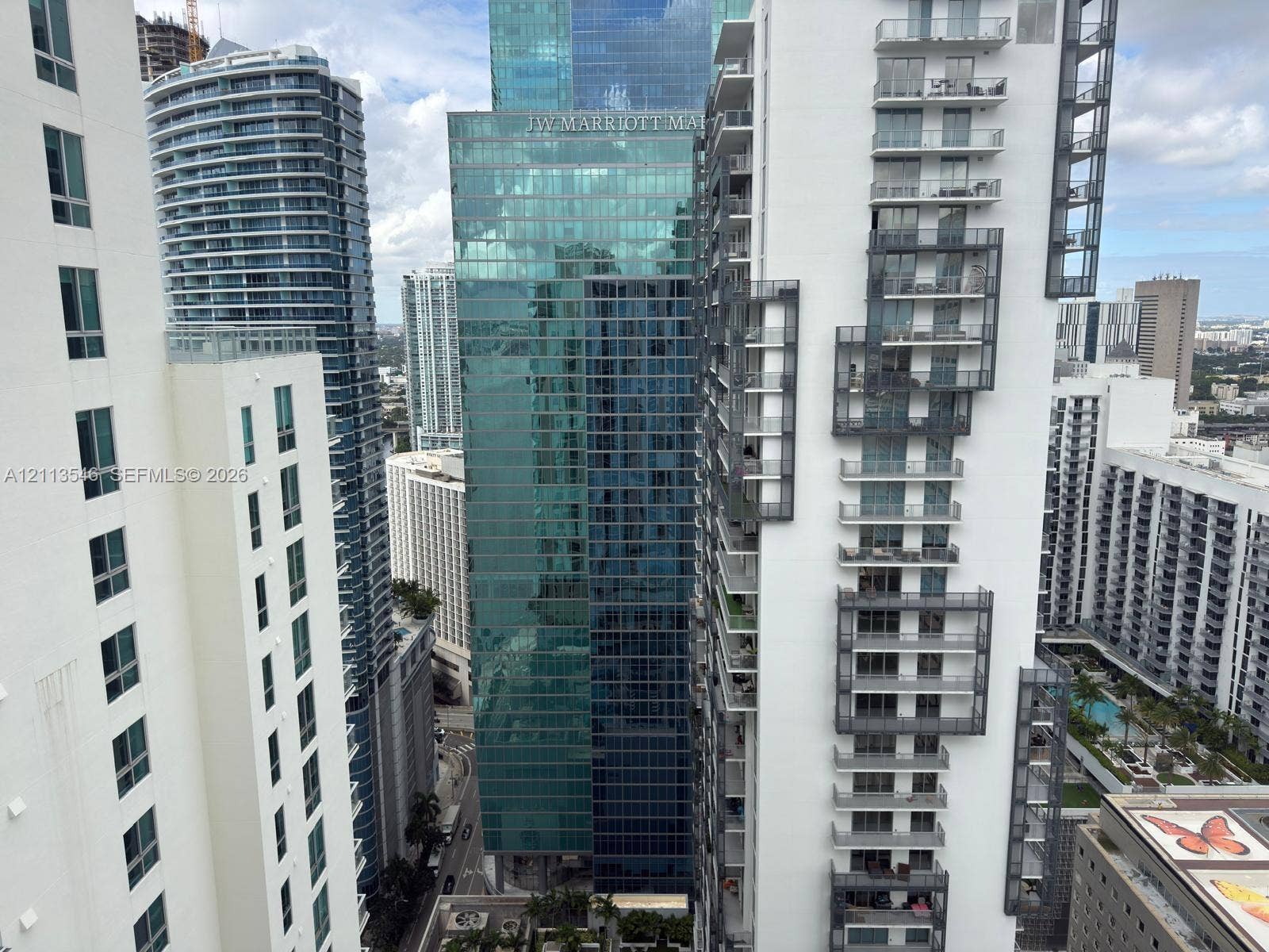 High-rise urban landscape featuring multiple glass-facade skyscrapers, architectural metal balconies, and dense metropolitan density