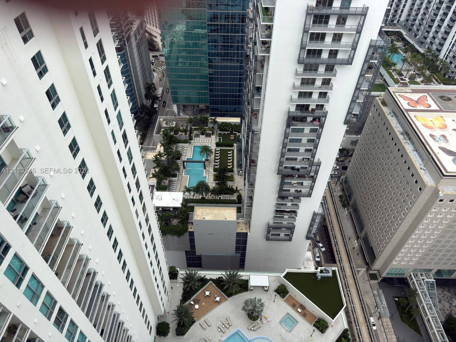 High-rise urban perspective featuring tiered balconies, a ground-level swimming pool, and an elevated terrace with manicured landscaping