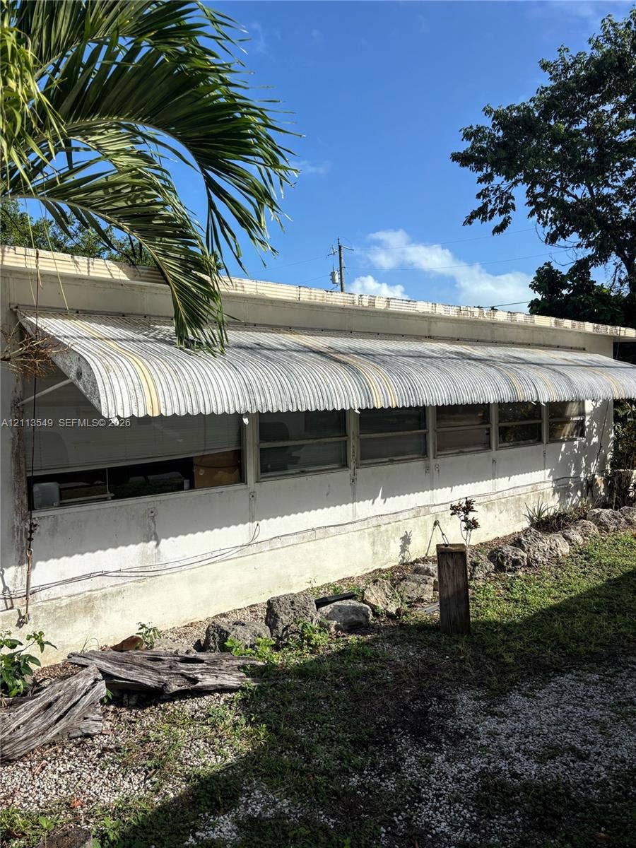 93 1st Court, Key Largo, FL 33037 Exterior profile featuring a metal-sided facade, horizontal sliding windows, and a corrugated metal awning