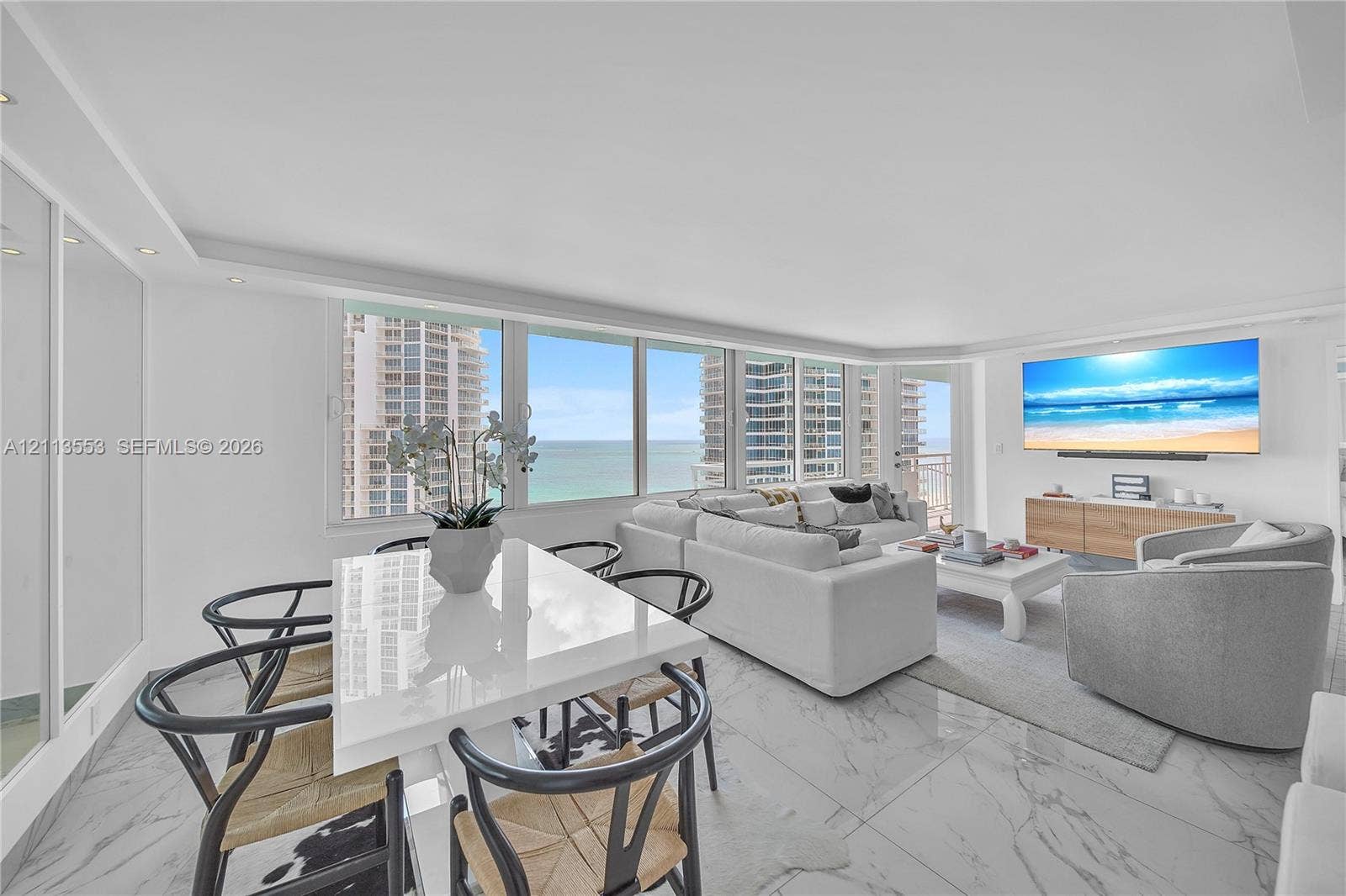 400 S Pointe Drive, #2106, Miami Beach, FL 33139 Open-concept living space featuring expansive floor-to-ceiling windows, polished stone-finish flooring, recessed lighting, and wall-mounted media cabinetry