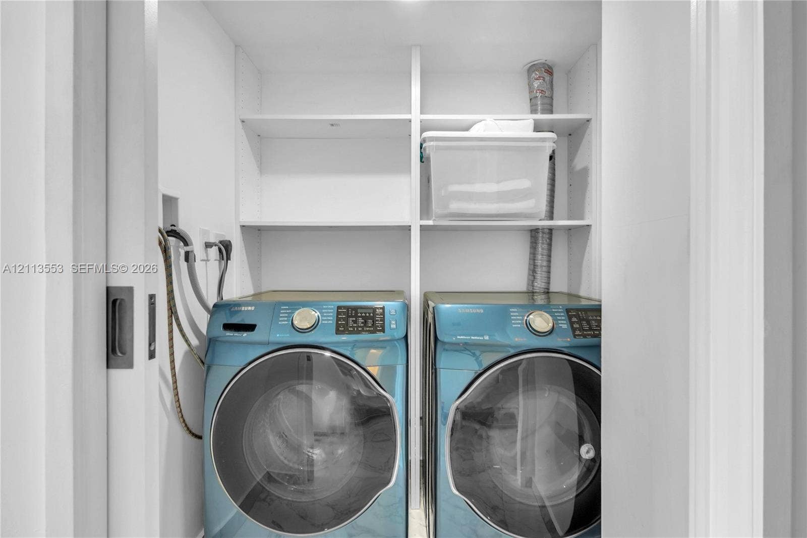 400 S Pointe Drive, #2106, Miami Beach, FL 33139 Laundry closet featuring built-in white shelving and a sliding pocket door