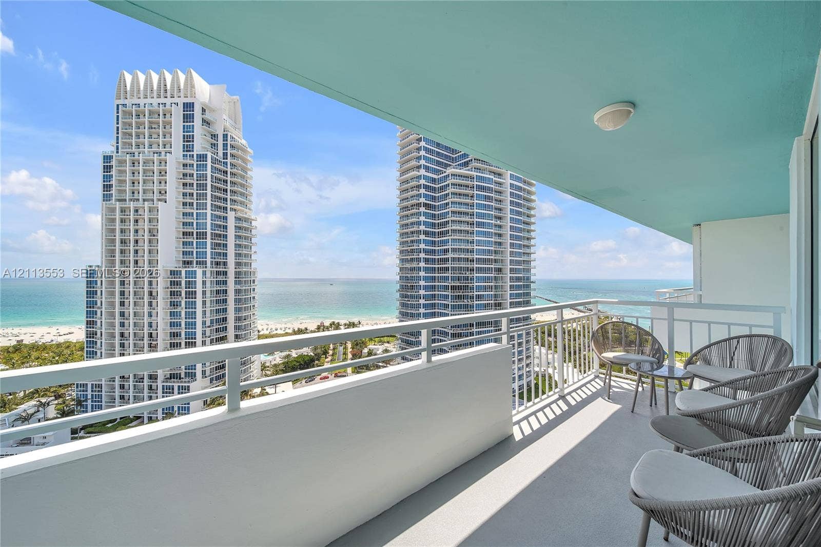 400 S Pointe Drive, #2106, Miami Beach, FL 33139 Covered balcony featuring a concrete floor, white metal railing, and ceiling-mounted lighting, showcasing a coastal horizon