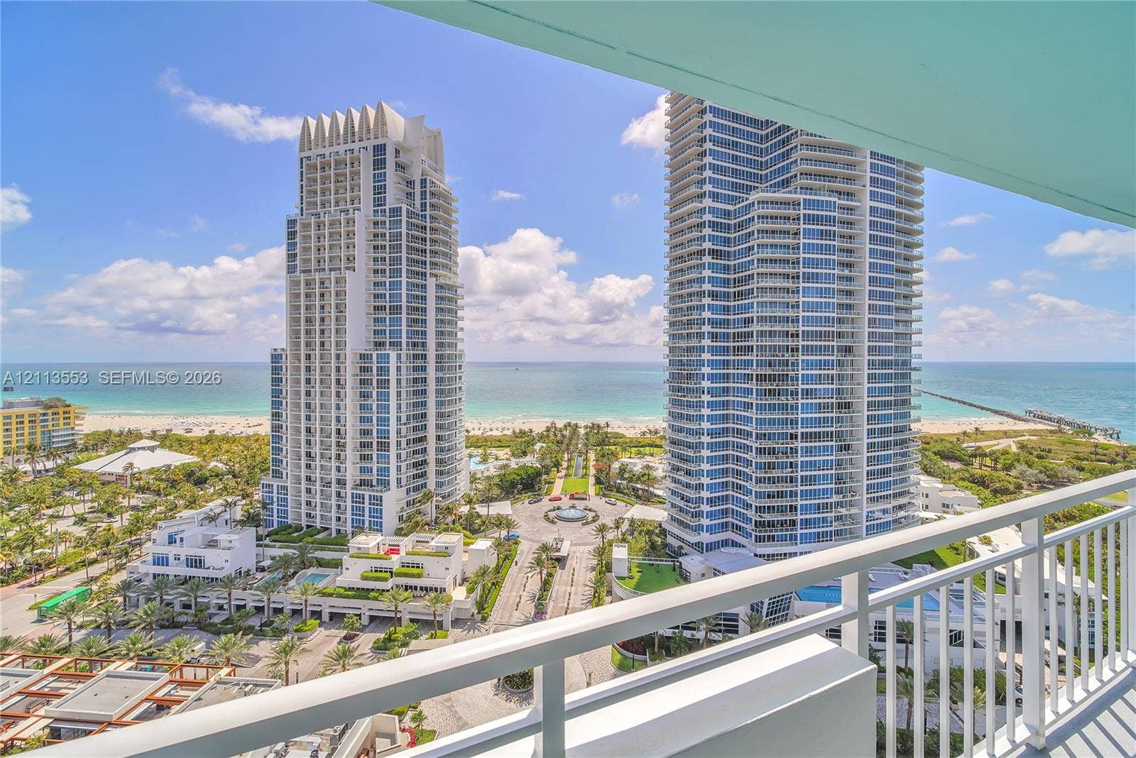 400 S Pointe Drive, #2106, Miami Beach, FL 33139 Covered balcony with white metal railings, overlooking coastal high-rise towers, sandy beach, and ocean horizon